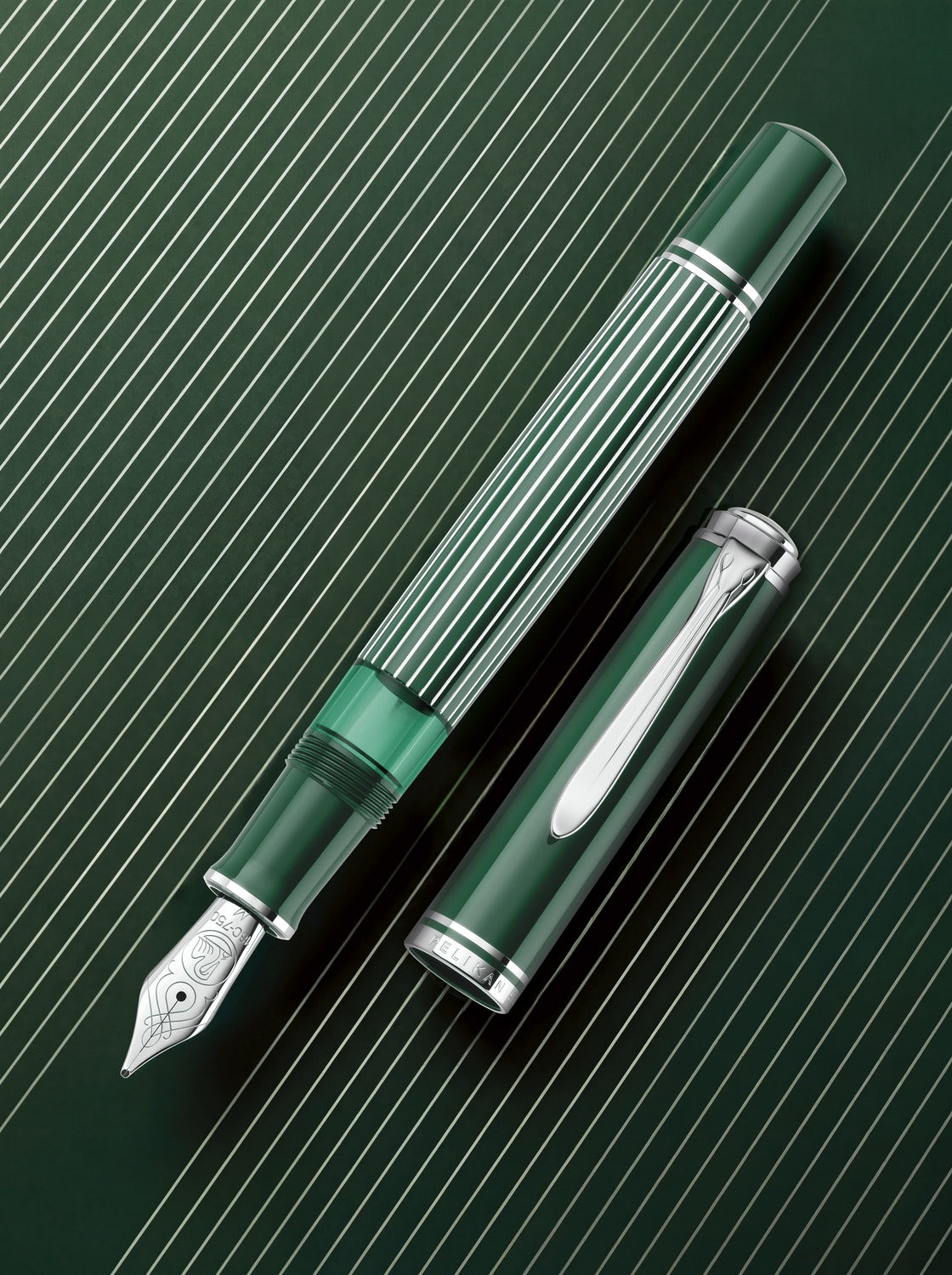Pelikan Souverän M815 Metal Striped Green – Füllhalter und Kappe auf grünem Hintergrund